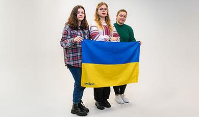 Three Ukrainian students hold their country's blue and yellow flag.
